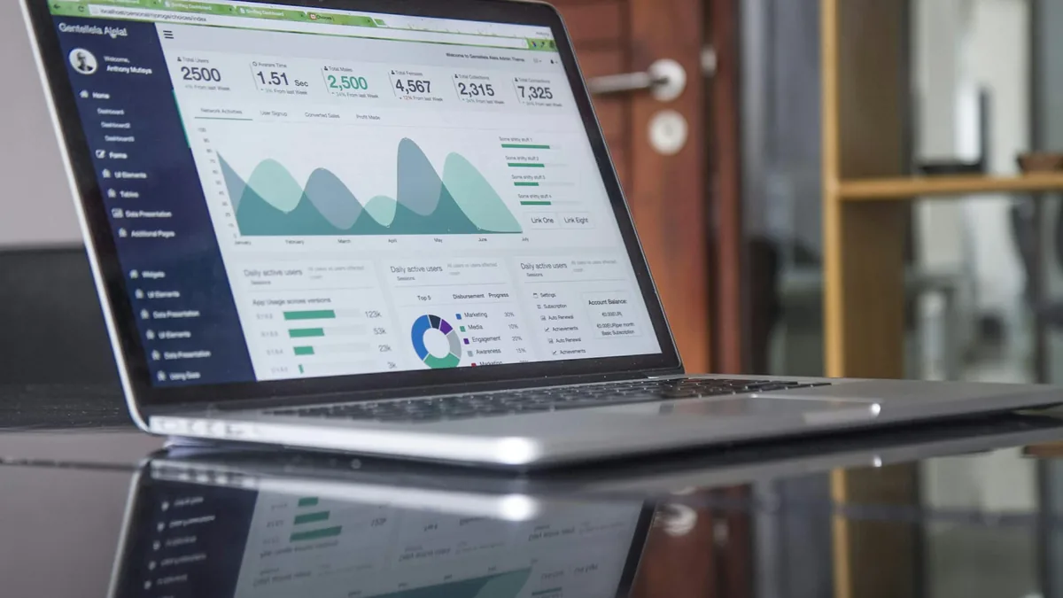 Modern laptop displaying digital performance analytics and workflow automation metrics on wooden office desk